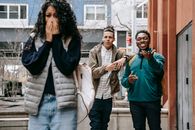 Young diverse men harassing female on street