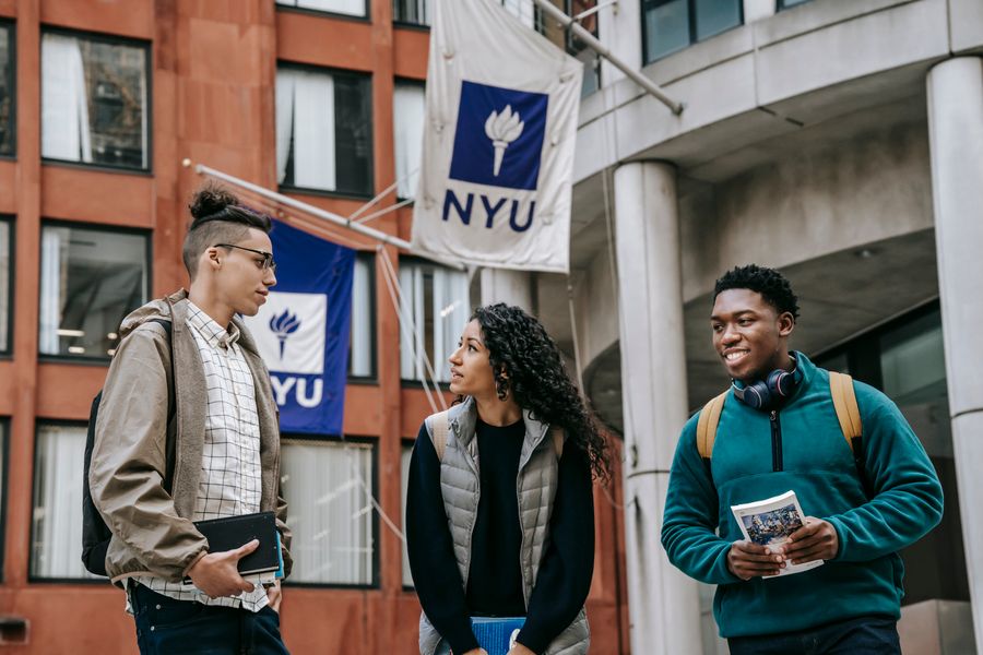 Diverse international students discussing university documents outside a campus building