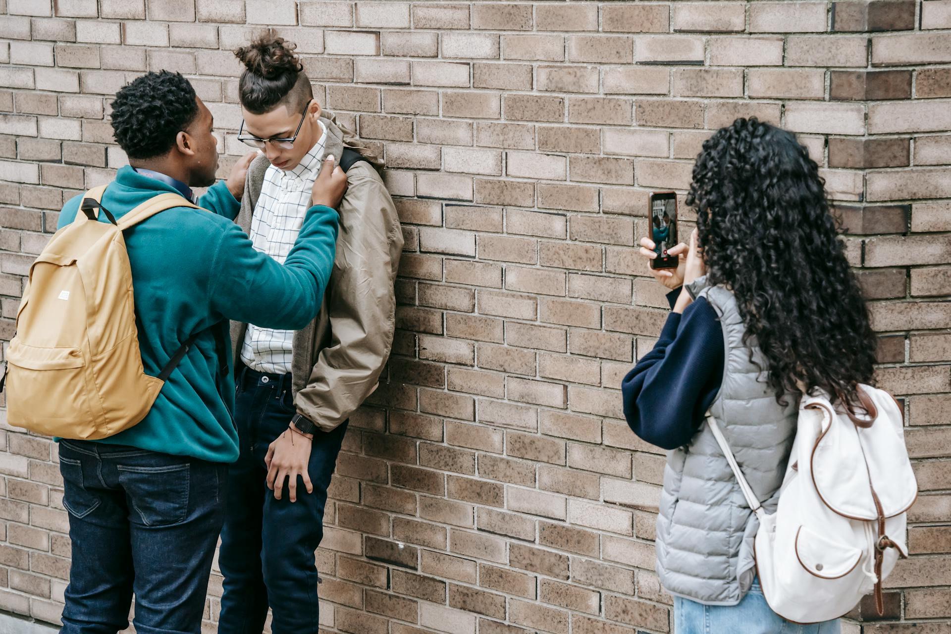 Des amis intimidant un camarade de classe près d'un immeuble.