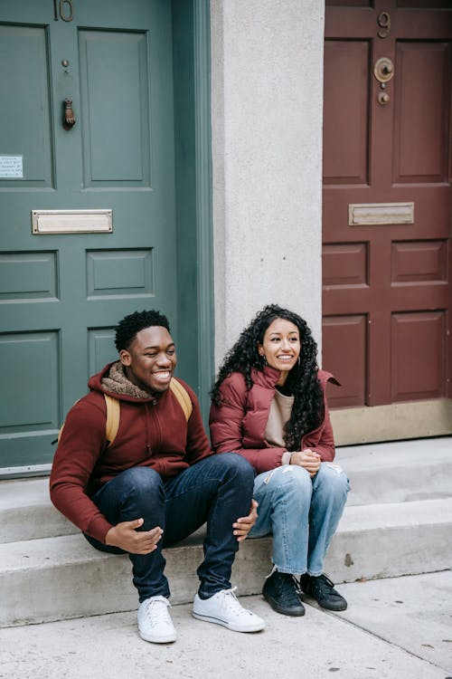 Multiethnic cheerful friends smiling on gray stairs of building