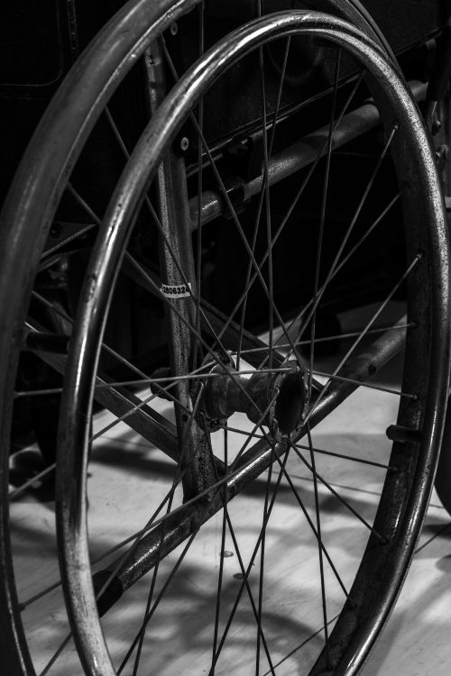 Free Detailed black and white image of a vintage wheelchair wheel, focusing on the metal spokes. Stock Photo