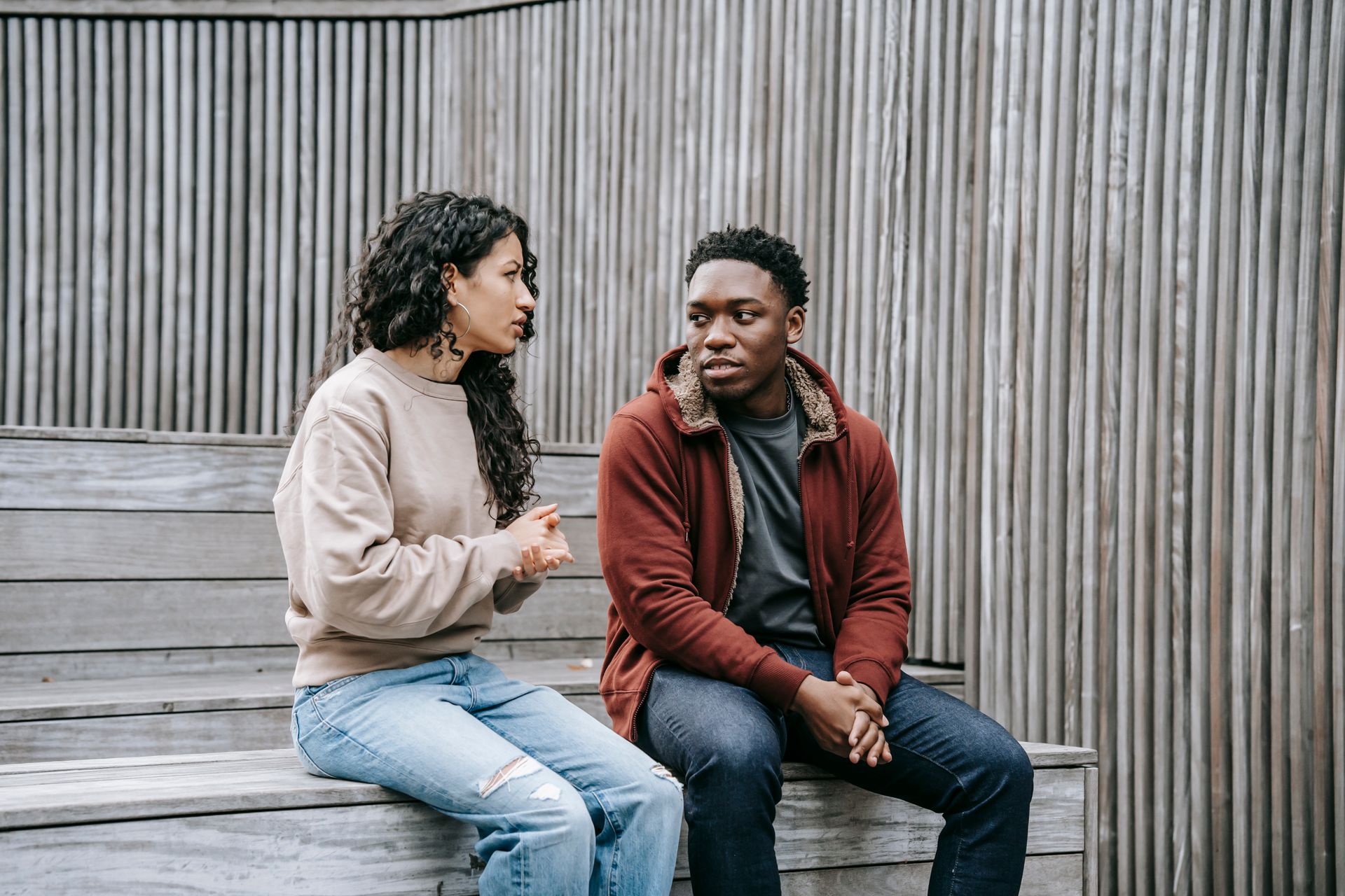A couple having a serious conversation while sitting on outdoor wooden stairs.