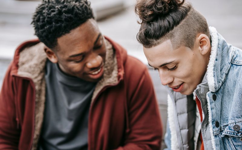 Two friends share a moment of easy conversation on a city stoop.