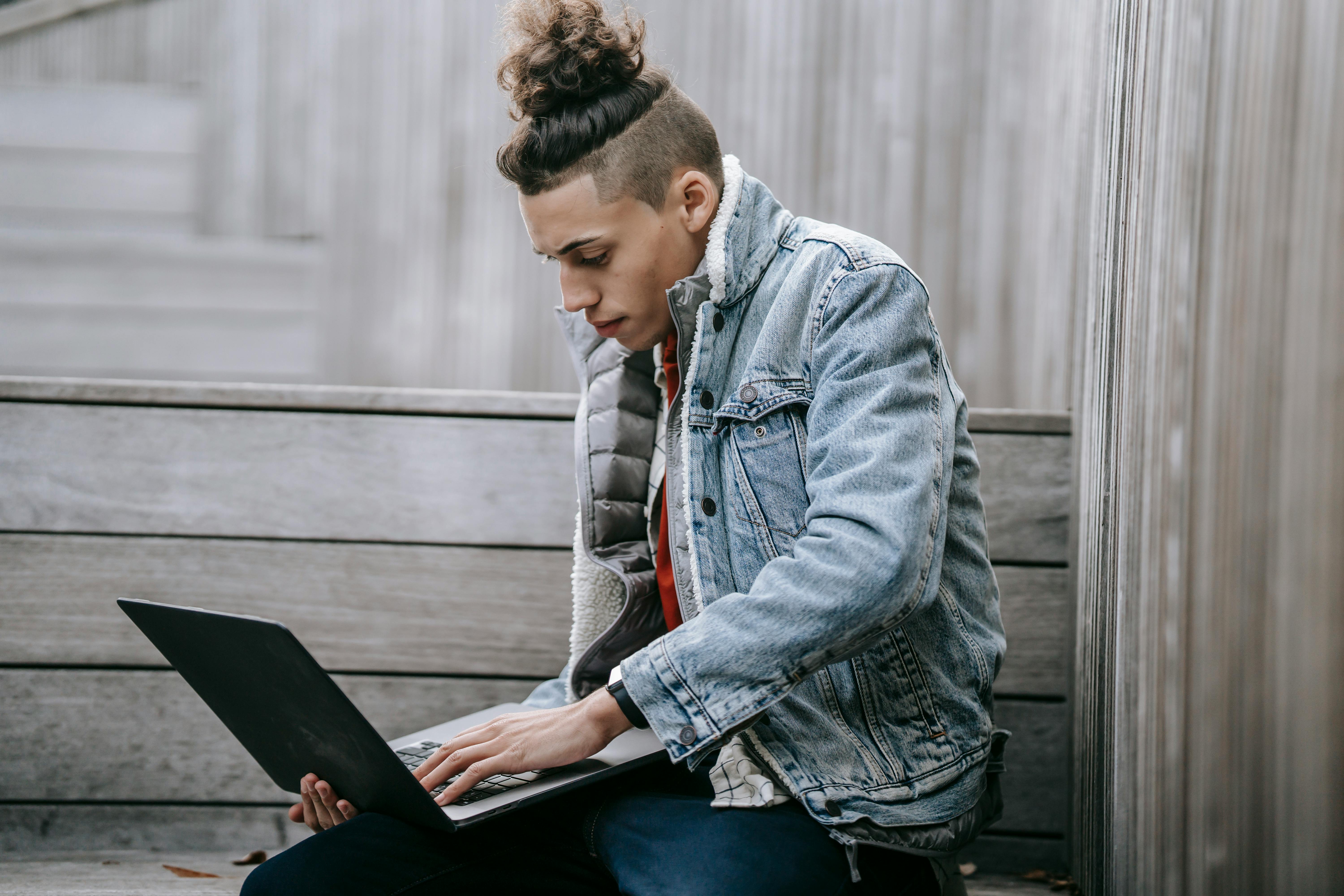 young man with trendy hairstyle using laptop