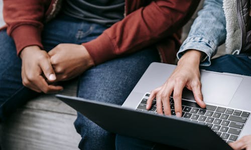 Friends using laptop sitting on bench