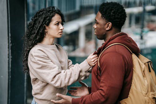 Free Side view of young unhappy diverse couple in casual clothes standing together and looking at each other Stock Photo
