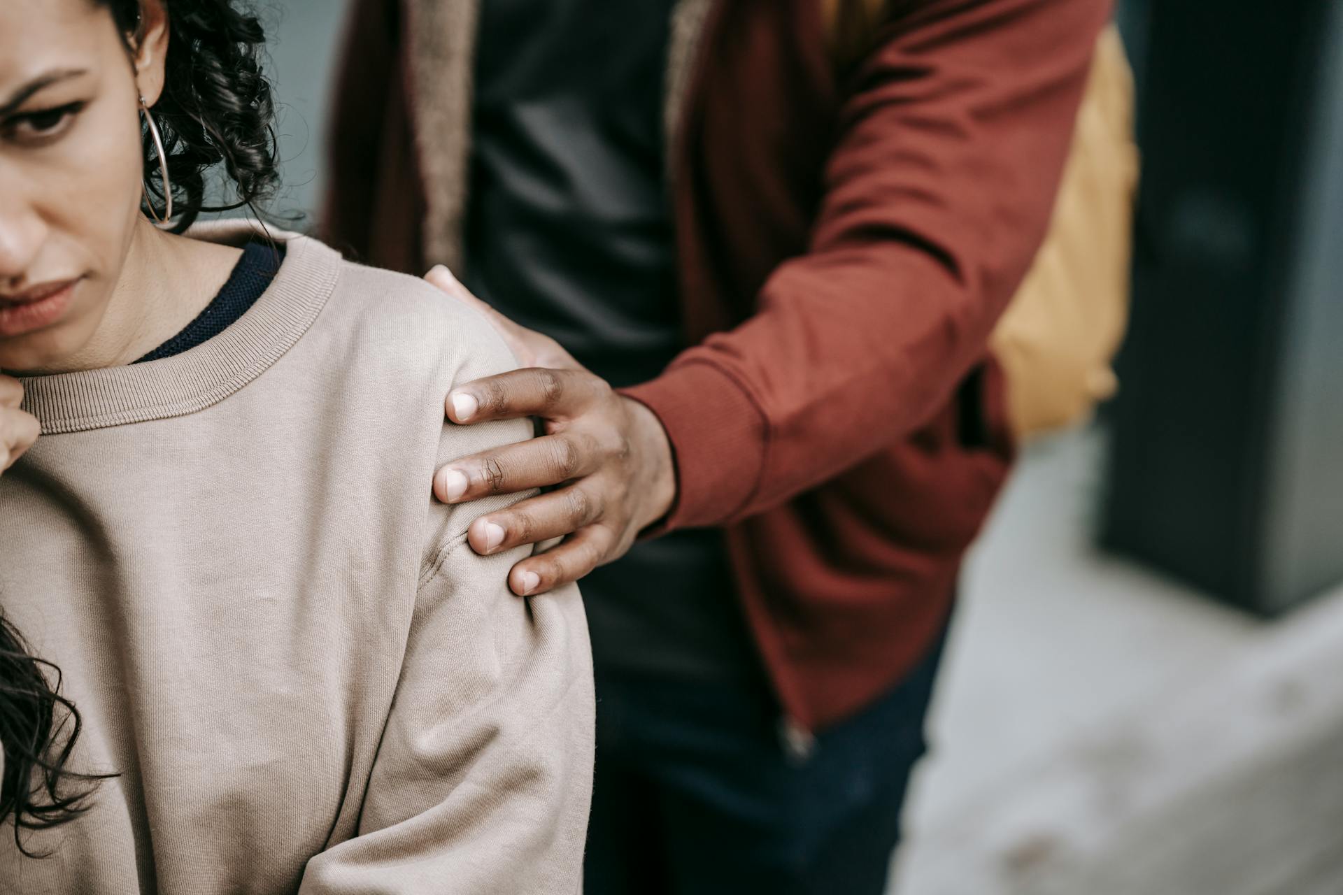 Crop unrecognizable unhappy young multiracial couple in casual outfit standing in city street while having conflict in daylight