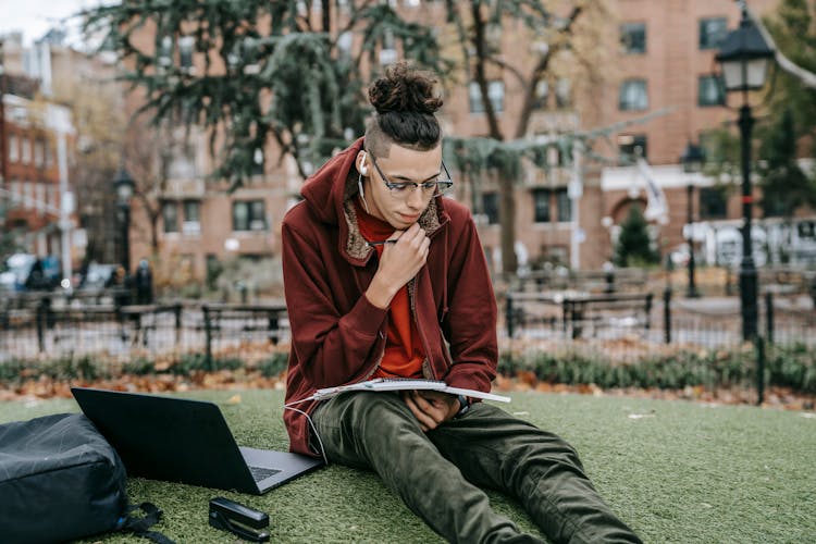 Guy Studying With Laptop And Notebook On Grass In Park