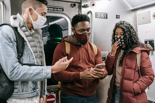 Free Faceless multiethnic students in masks in subway train with phone Stock Photo