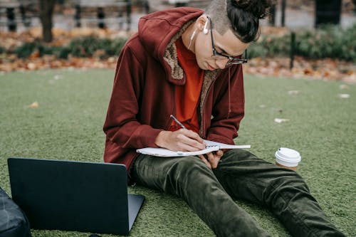 Femme En Veste Rouge Livre De Lecture Alors Qu'il était Assis Sur L'herbe Verte