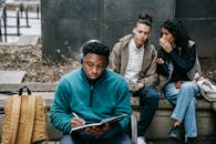 Multiracial students gossiping about black man with notepad