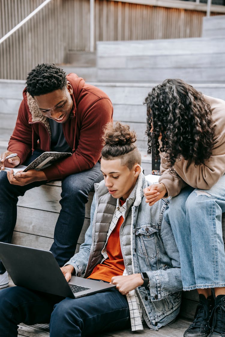 Unrecognizable Diverse Friends Sharing Laptop On Urban Stairs