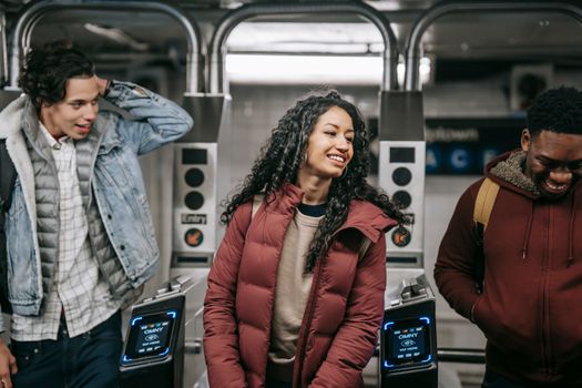 Crop smiling multiracial friends talking in underground