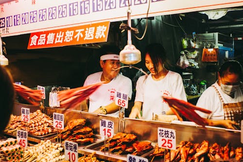Vendors Selling Food while Standing in front of the Food Stall