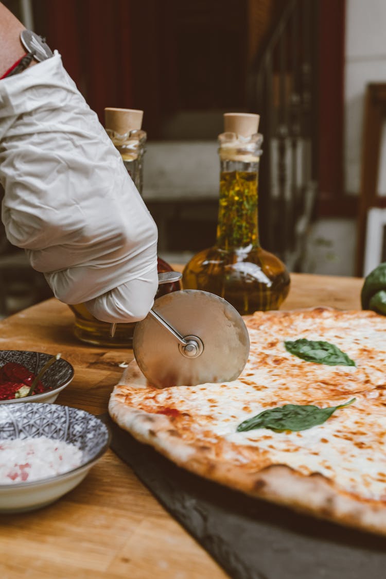 Person Cutting An Italian Style Pizza