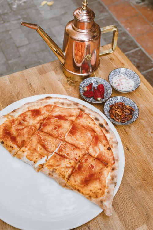 Free Top view of Italian cheese pizza with copper kettle and condiments, perfect for food blogs. Stock Photo