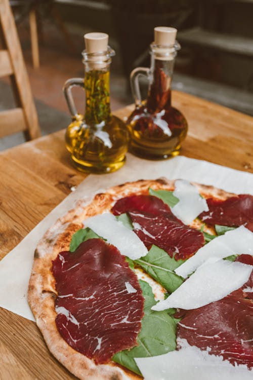 Italian Style Pizza on a Table and Two Bottles with Olive Oil 