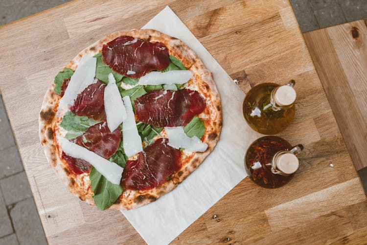 Pizza With Red Meat Toppings On Wooden Table