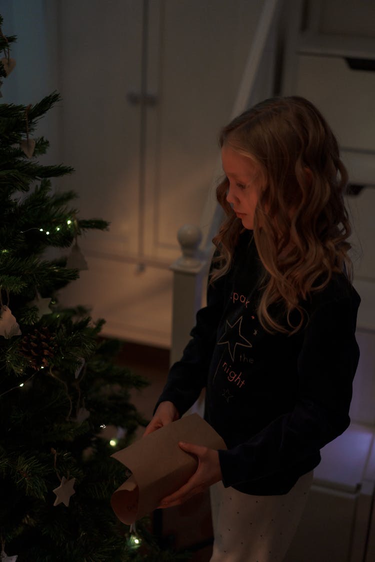 Girl In Black Sweater Standing Beside The Christmas Tree