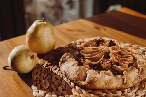 Free A delicious pear galette on a wooden table, embodying autumn warmth. Stock Photo