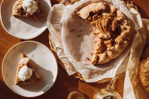 Free Rustic apple galette with vanilla ice cream on plates in warm sunlight. Stock Photo