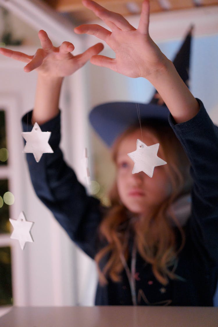 Girl In Wizard Costume Doing Magic Trick With White Star Ornaments