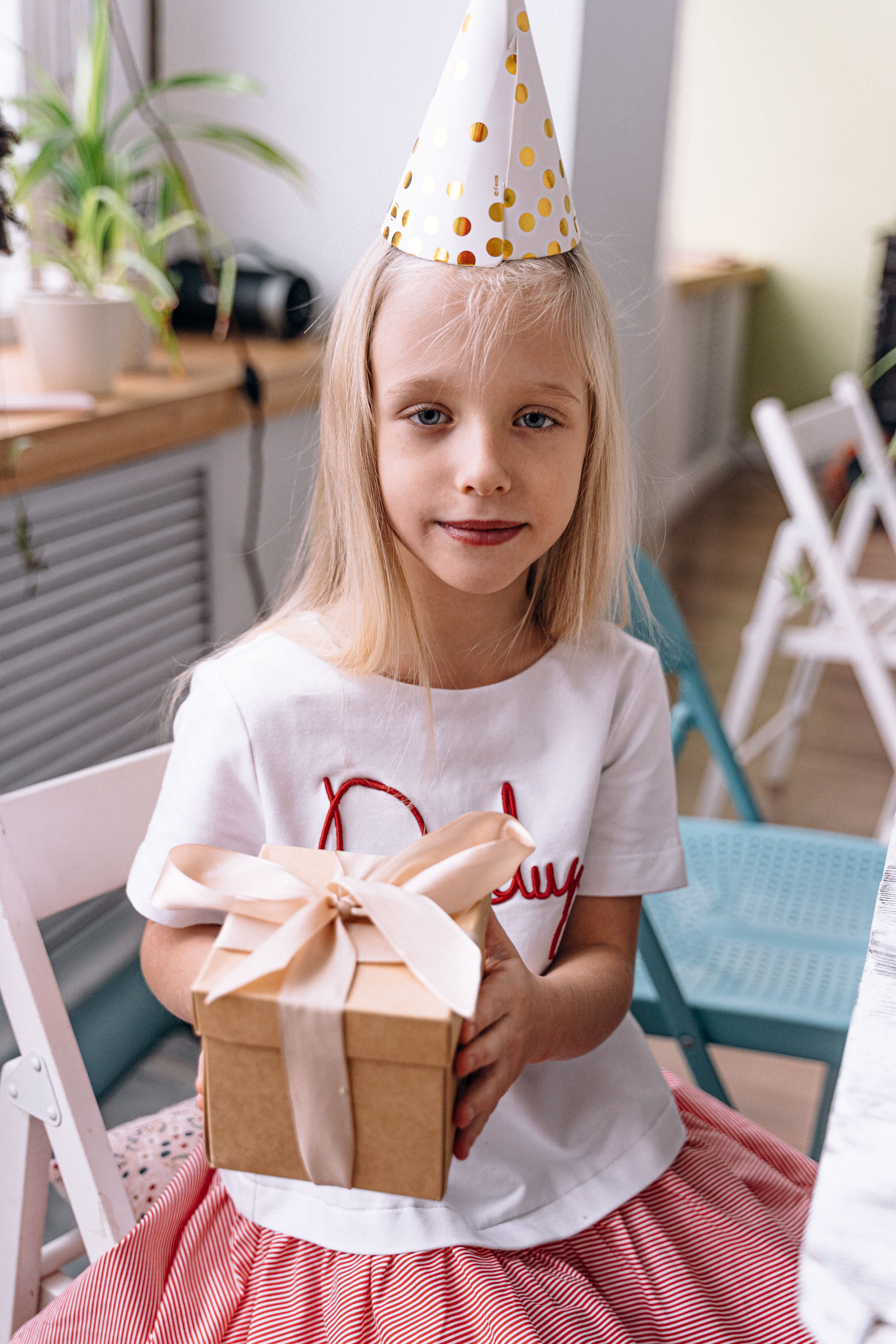 Little Girl in a Birthday Hat Holding a Present · Free Stock Photo