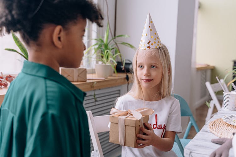 Girl Giving A Gift To A Friend At The Birthday Party 