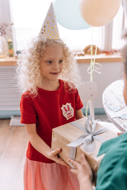 Girl in Red Crew Neck T-shirt Holding Brown Box