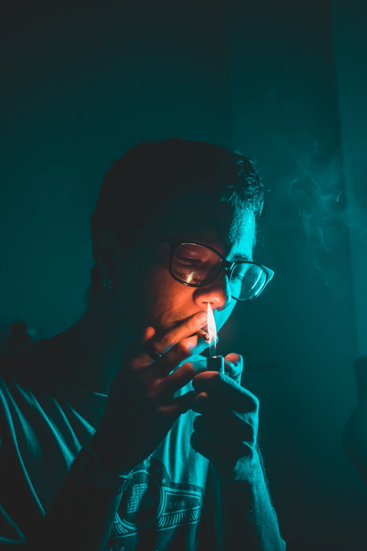 Portrait Of Man Lighting Cigarette In Dark