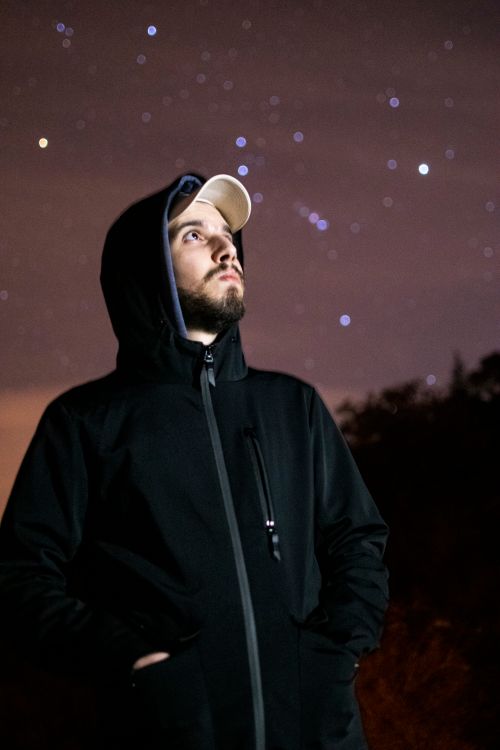 Free A bearded man looks up at a starry sky in Algeria, dressed warmly in a hoodie and jacket. Stock Photo