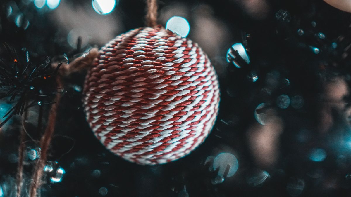 Yarn craft ideas with a red and white yarn ornament hanging on a tree
