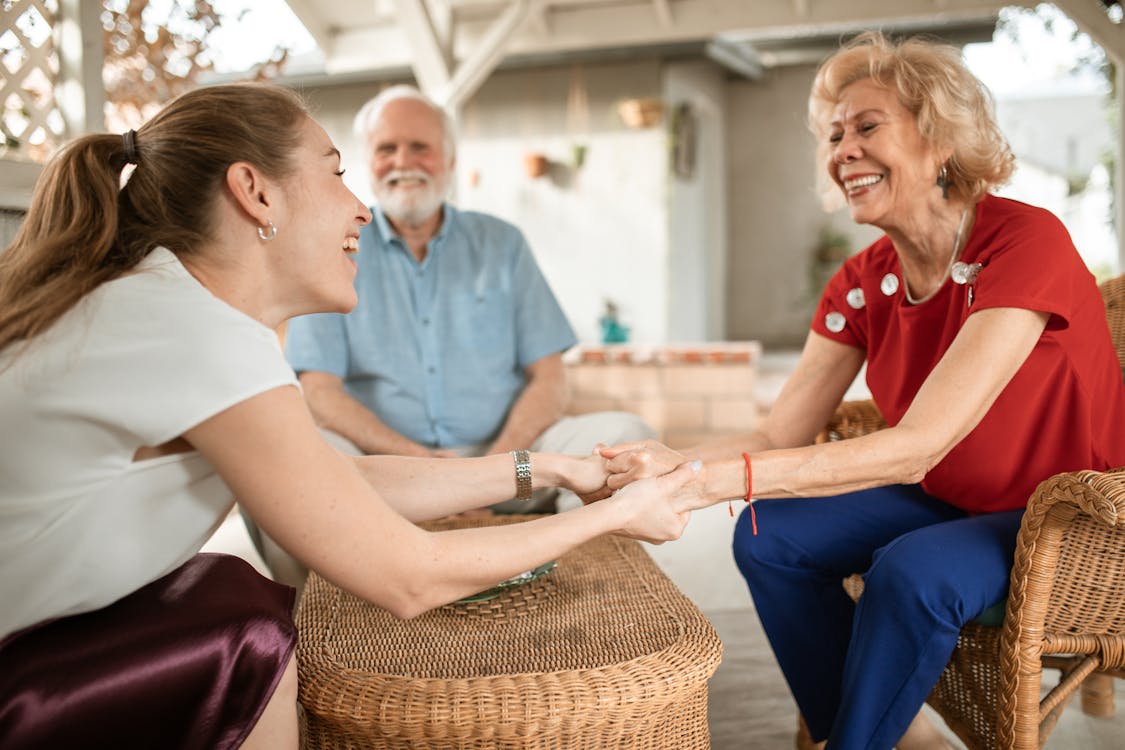 Free Young Woman and Elderly Couple Talking and Smiling Stock Photo