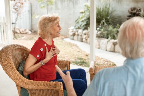 Free Senior woman in red shirt smiling and conversing in a garden setting. Stock Photo