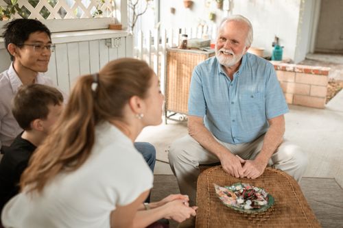 Free Elderly man enjoying a pleasant family gathering outdoors with diverse group sitting together. Stock Photo