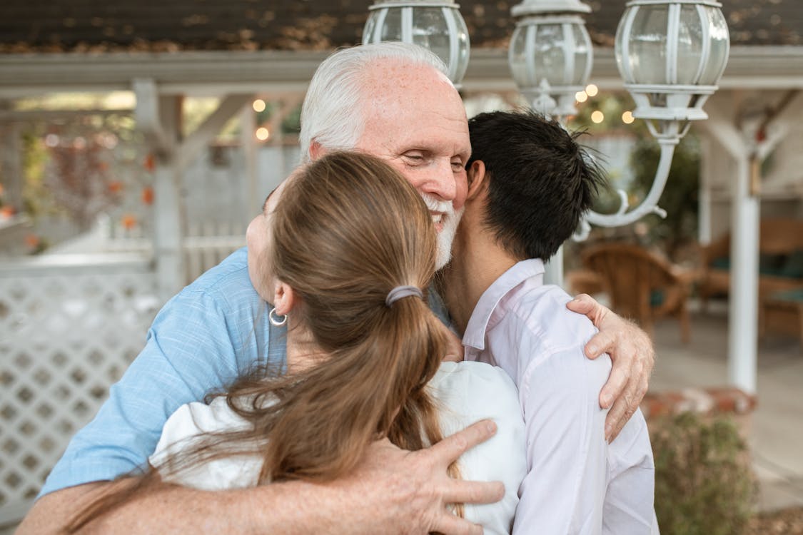 Elderly Man Hugging Young Couple