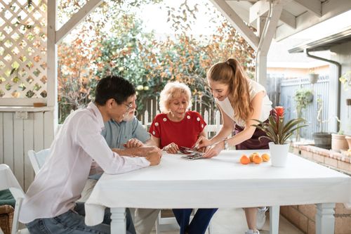 Free Family sharing photos while seated outdoors, surrounded by nature and smiles. Stock Photo