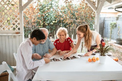 Free A happy family gathered around a table, sharing memories while looking at photos. Stock Photo