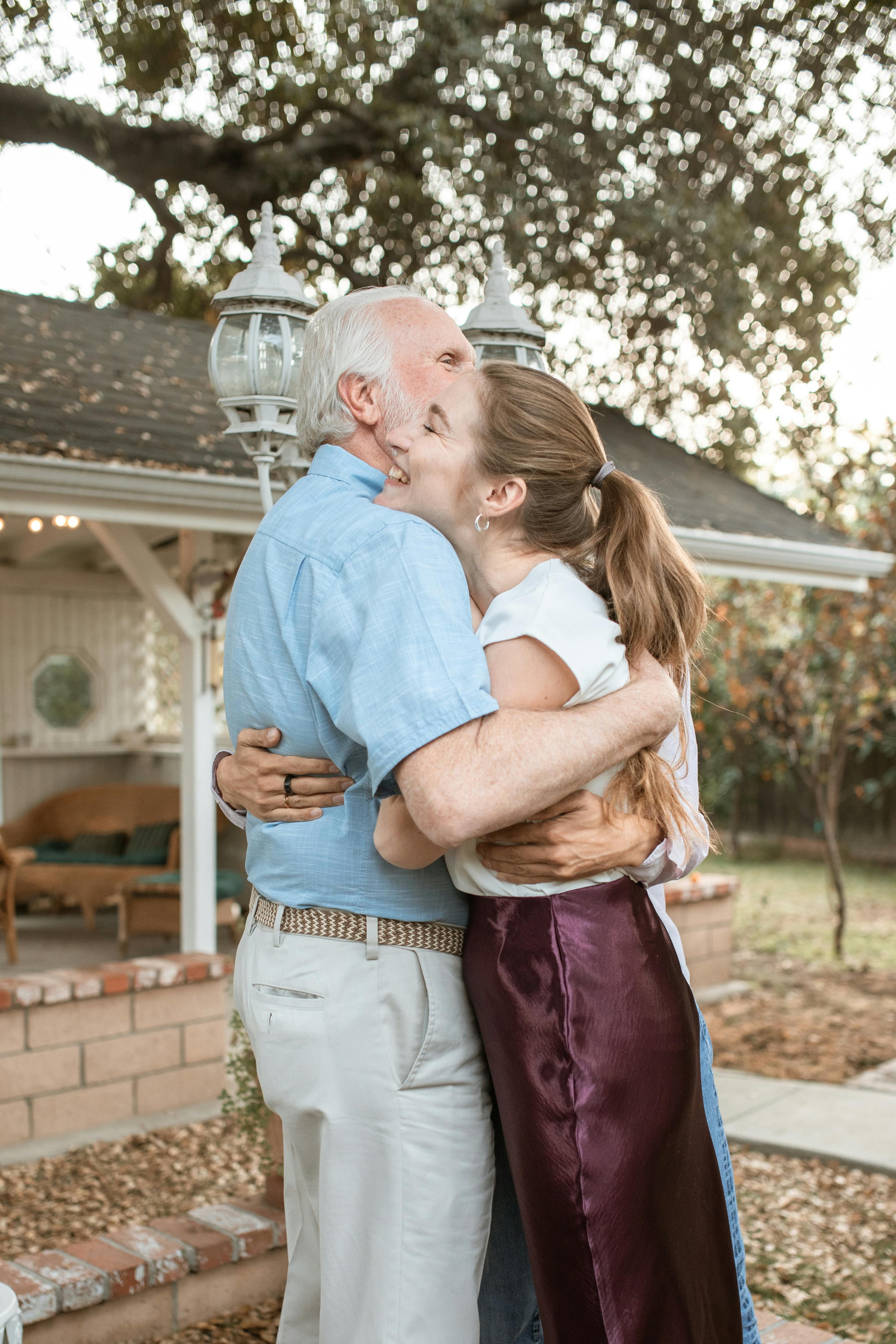 man in blue polo shirt kissing woman in white sleeveless shirt