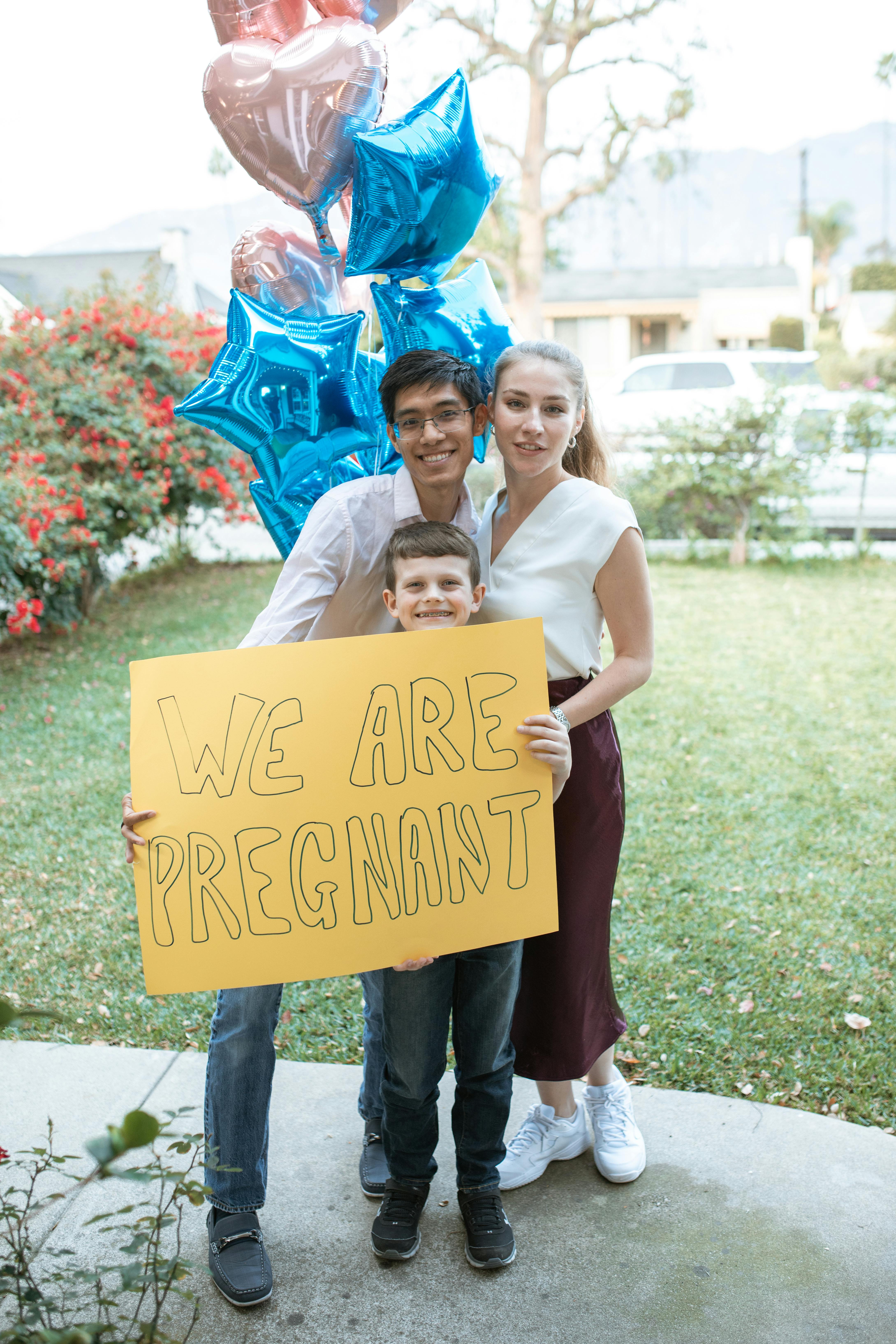 2 women holding yellow and red happy birthday signage