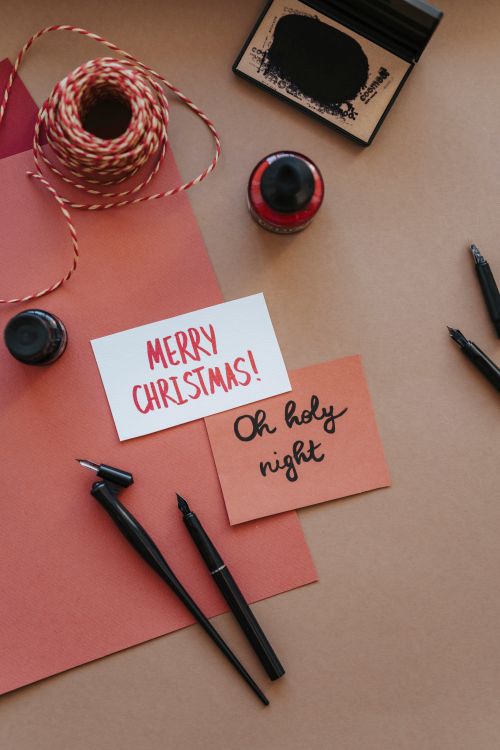 Free Elegant flatlay with Christmas card calligraphy and writing tools. Perfect for holiday greetings. Stock Photo
