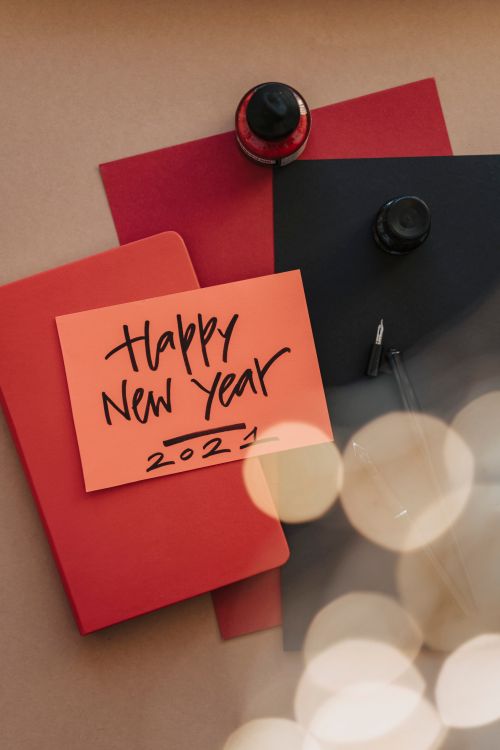 Free A flat lay of a New Year 2021 card with bokeh lights, ink bottles, and notebooks. Stock Photo