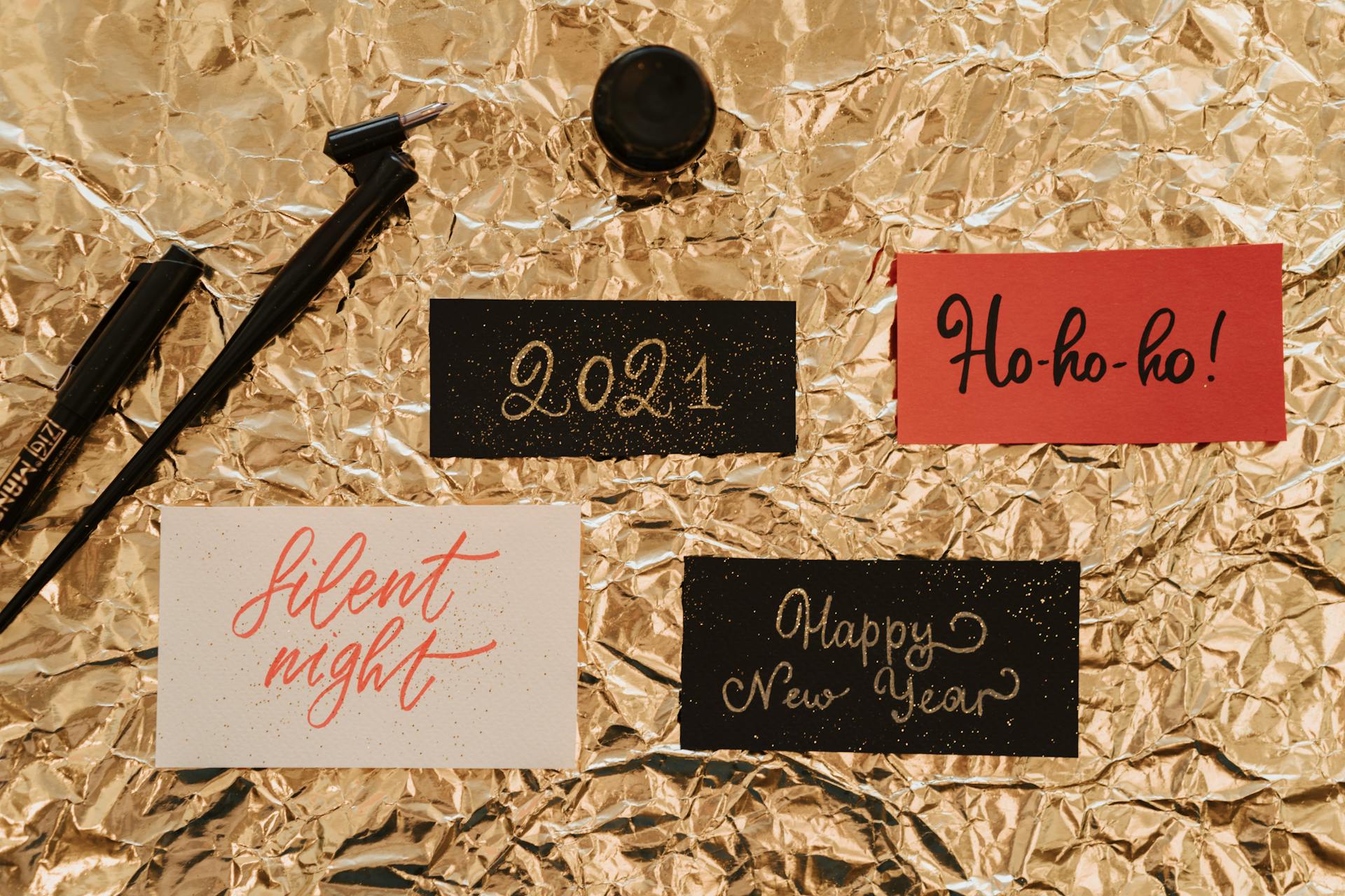 Holiday-themed calligraphy on gold foil creates a festive mood with New Year and Christmas messages.
