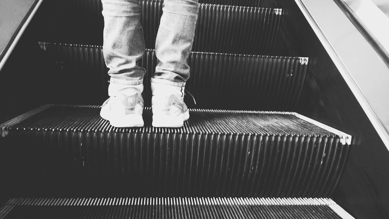 Free Grayscale Photo of Person Standing on Esclator Stock Photo
