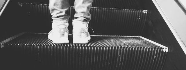 Black and white photo of feet on an escalator, highlighting movement and modern travel.