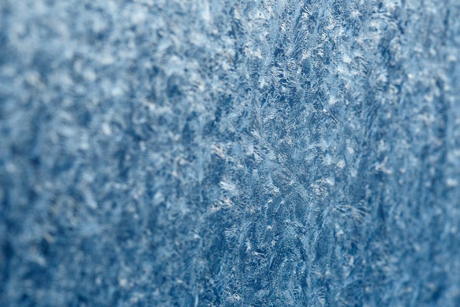 Detailed macro shot of intricate frost texture on a window during winter.