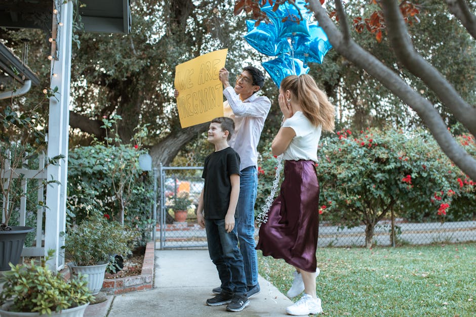 Family joyfully reveals pregnancy in a garden setting with balloons.