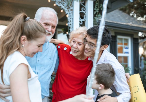 Family embracing elderly grandparent outdoors