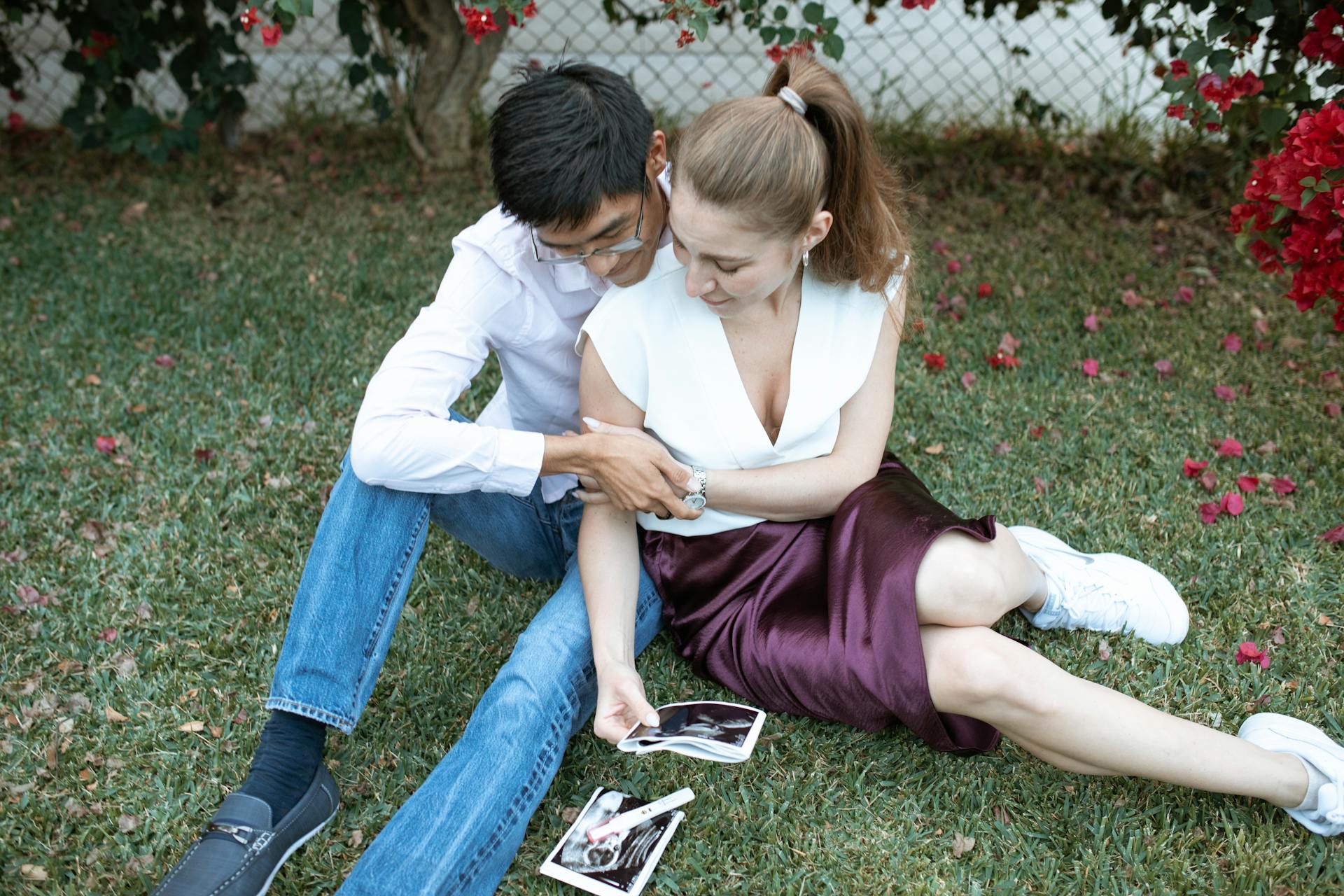 Couple Sitting on Grass While Looking at the Ultrasound Images