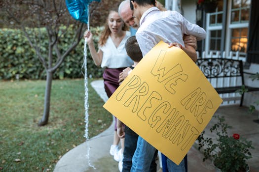 A family holding a sign announcing pregnancy, filled with joy and celebration outdoors.